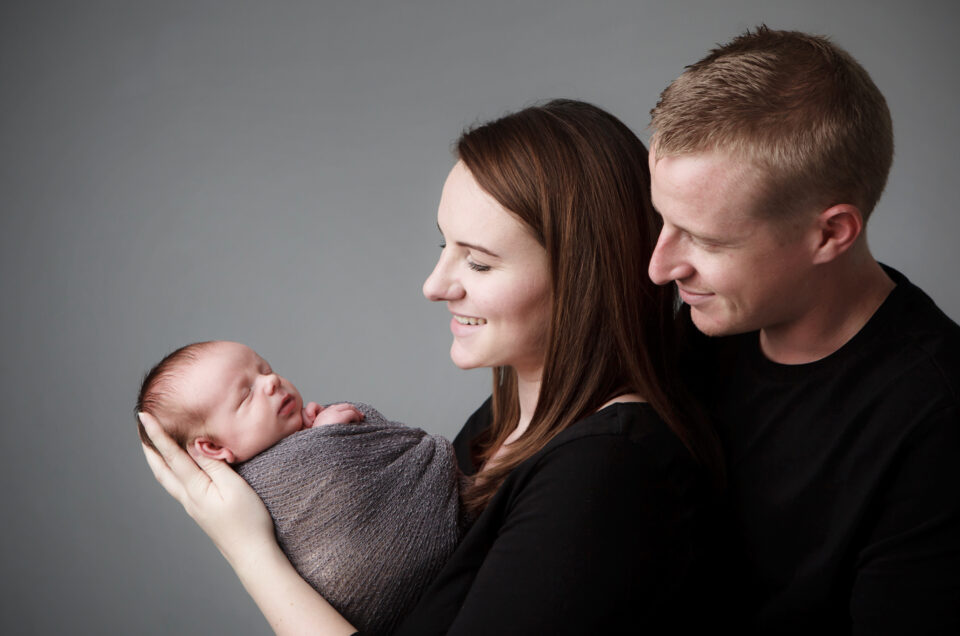 Parents holding their newborn baby in a studio family portrait at Sweetlife Studio North Lakes