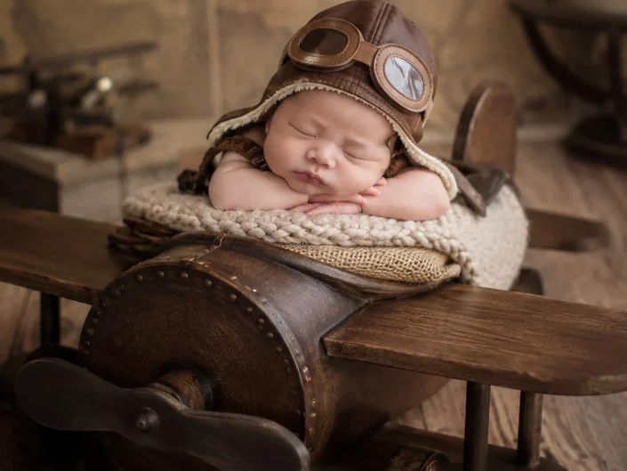 Sleeping newborn dressed as an aviator in a wooden aeroplane at Sweetlife Photography North Lakes