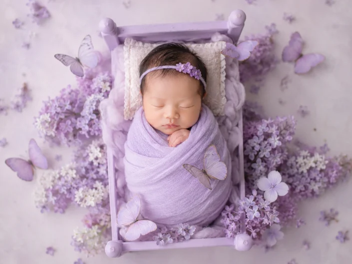 Sleeping newborn wrapped in lavender among flowers and butterflies at Sweetlife Photography North Lakes